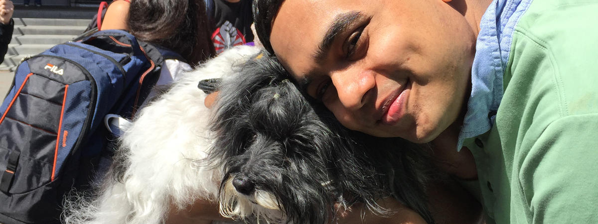 photo of a male student cuddling with a terrier during Pet Hugs, a University Health Services event